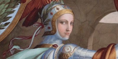 A woman in armor. Her helmet is adorned with a large copper bird. She is holding a lance.